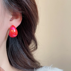 Macro shot of minimalist rose red teardrop acrylic stud earring on female model