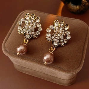 Macro shot of vintage gold earrings with filigree work and brown pearl on velvet