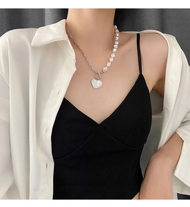 Detail of a pearl and titanium heart pendant necklace worn on a model with T-bar clasp