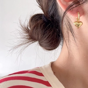 Close-up of model wearing gold heart-shaped hoop earrings in 925 sterling silver