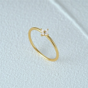 Macro view of gold clover ring featuring four sparkling cubic zirconia on a white background