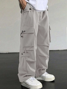 Detail of light gray baggy cargo pants featuring utility pockets and drawstring cuffs