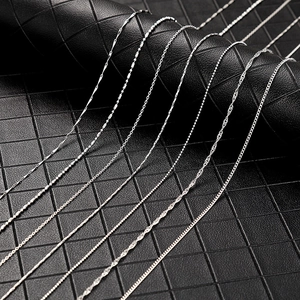 Detailed view of multiple silver chain styles including snake and wave patterns on leather