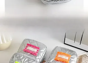 Gros plan de la trousse de maquillage en similicuir argenté avec étiquette brodée