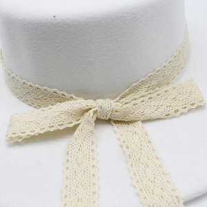 Détail d'un chapeau en feutre blanc orné d'un ruban en dentelle et d'un nœud élégant