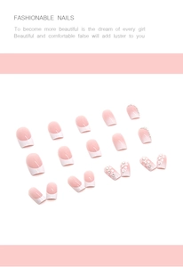 Detail of nude press-on nails featuring white French tips, 3D floral accents, and rhinestones