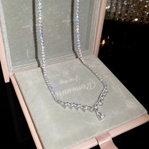 Detailed shot of silver pear-shaped zircon necklace in a premium pink gift box