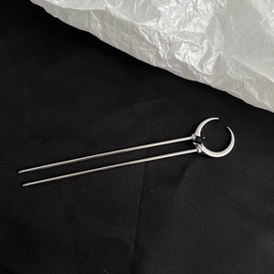 Detail of silver metal hair stick with crescent moon head and black square gemstone