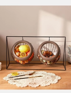 Close-up of hanging dark brown iron fruit baskets on a black metal stand in sunlight