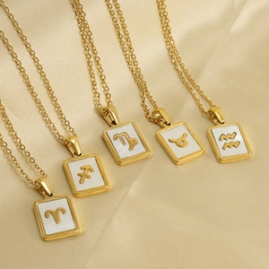 Detail of five 18K gold-plated zodiac pendant necklaces with white inlay symbols