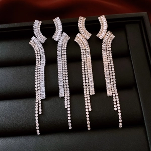 Macro view of geometric fringe earrings with sparkling zircons in silver and gold