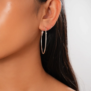Close-up of a silver large hoop earring worn by a model to show its size and shiny finish