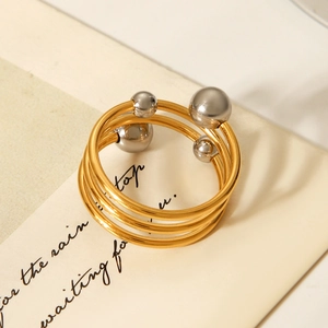 Detailed view of layered gold steel ring with silver beads on vintage paper background