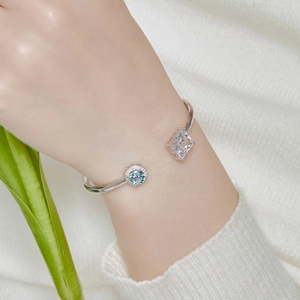 Macro shot of a silver cuff bracelet with blue and clear square zircons on a white sweater