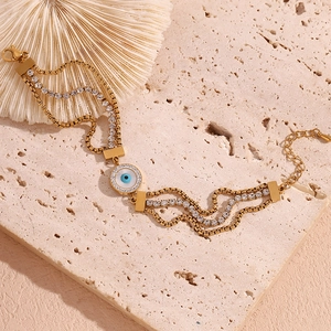 Detail of 18K gold plated multi-layer chain bracelet featuring blue evil eye and zircons