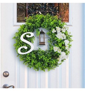 Eucalyptus Christmas wreath with white flowers and bronze lantern on a white door