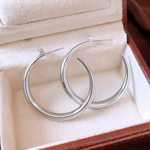 Macro detail of silver geometric hoop earrings with small zircon accents in jewelry box