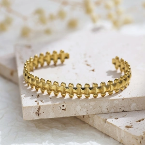 Detailed macro shot of a golden geometric textured open bangle with modern industrial design
