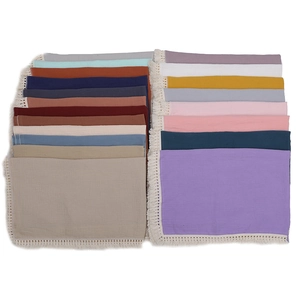 Macro detail of soft muslin baby blankets featuring decorative fringe and crinkle texture