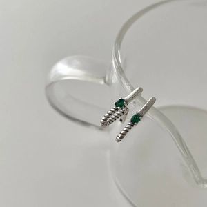 925 sterling silver drop earrings with green zircon gems displayed on a glass rim