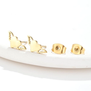 Detail view of gold heart stud earrings with angel wings on white stone display