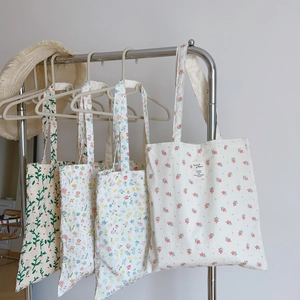 Selection of floral canvas tote bags with botanical patterns hanging on a metal rack