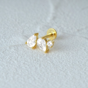 Close-up of gold cartilage stud with three clear pear-shaped gems and flat back disc