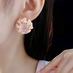 Detailed close-up of a pink floral stud earring with a central translucent gemstone