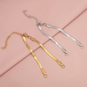 Dettaglio di catene piatte a serpente color oro e argento con chiusura a moschettone e catenina