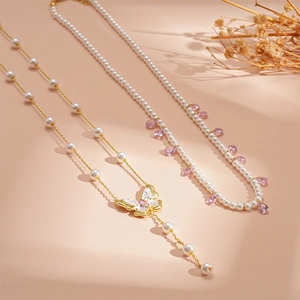 Detail of elegant butterfly and pink teardrop crystal necklaces with faux pearls
