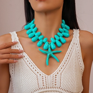 Detail of turquoise acrylic starfish pendant necklace worn on a white V-neck sweater