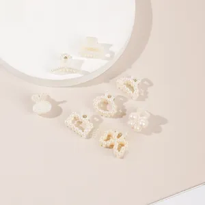 Macro shot of assorted pearl hair clips featuring butterfly and rabbit shapes on white podium