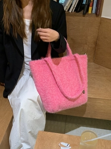 Dettaglio di una borsa tote rosa in morbido peluche in una calda atmosfera di biblioteca