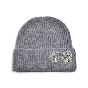 Détail d'un bonnet en maille gris foncé avec un nœud décoratif orné de strass brillants