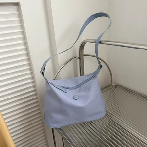 Light blue nylon crossbody bag with minimalist curved design on a metal rack