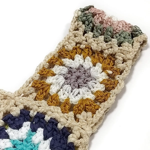 Macro shot of colorful crochet granny square stitching on a handmade bohemian handbag strap