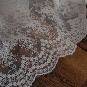 White floral lace tablecloth background with delicate embroidery on dark wood