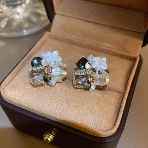 Detail of vintage flower earrings with grey crystals and pearls on a brown velvet box