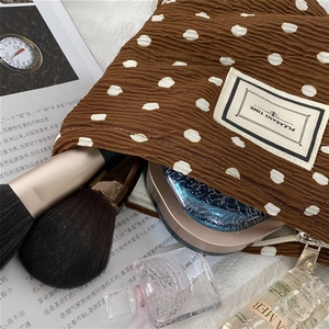 Detail of coffee brown polka dot makeup bag with pleated texture and storage capacity