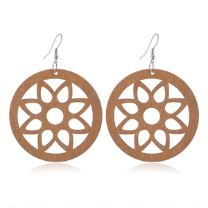Detailed view of hollow floral wooden earrings with metal hooks on white background