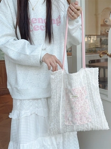 White lace canvas tote bag with pink straps and floral embroidery shown in a lifestyle setting