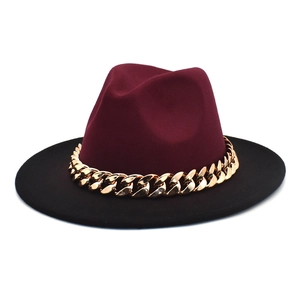 Detail of burgundy and black fedora hat with a chunky gold chain strap decoration