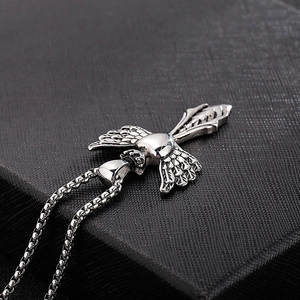 Macro shot of silver stainless steel heart pendant with angel wings on a black box