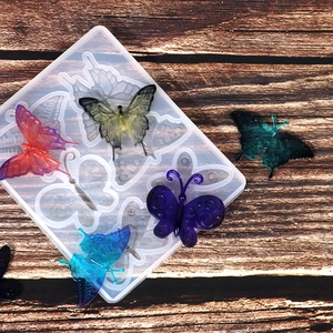 Détail du moule en silicone papillon et pendentifs en résine colorés sur fond de bois