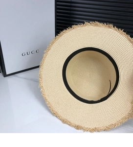 Close-up of beige straw sun hat featuring trendy frayed edges and black interior ribbon