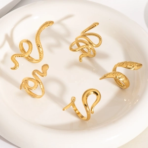 Detailed view of five gold snake rings with scales and coiled designs on a white plate