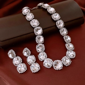 Detailed view of vintage silver crystal necklace and earring set on brown silk fabric