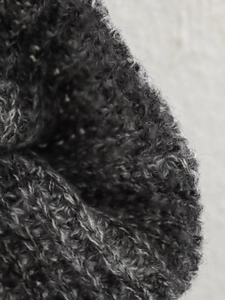 Vista macro che mostra la spessa trama a maglia e le fibre di lana grigia sul capo
