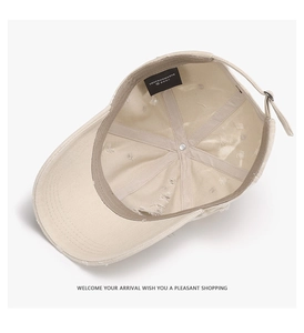 Detail of beige cotton baseball cap featuring an adjustable metal buckle and inner lining