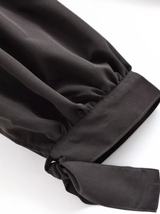Detailed view of black lantern trousers featuring cinched cuffs and elegant bow-tie ribbons